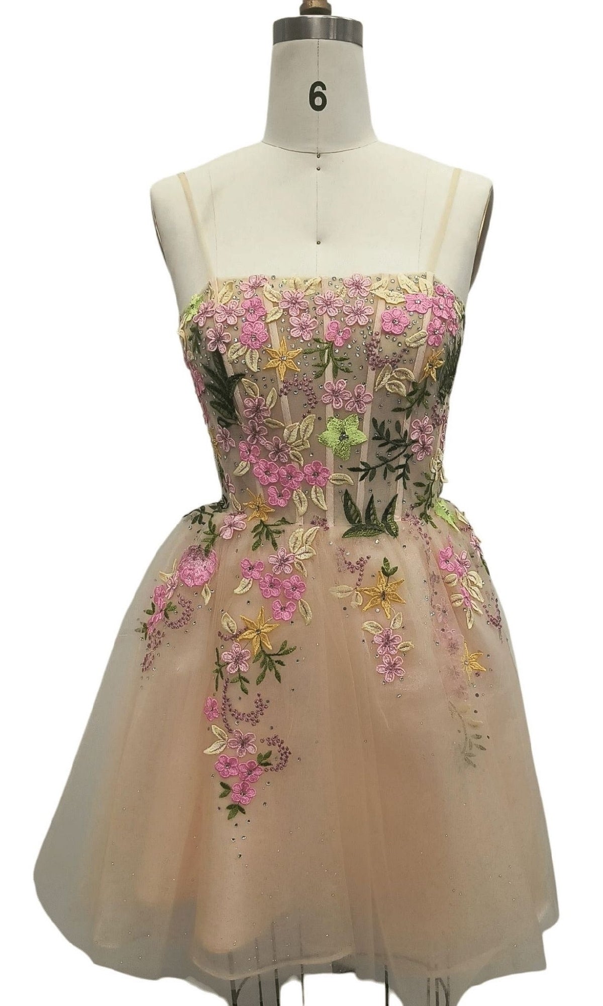 The Beaded Short Nude Hoco Dress: 12485 is a sleeveless tulle homecoming dress with pink, green, and yellow floral embroidery, creating a charming party-ready look.